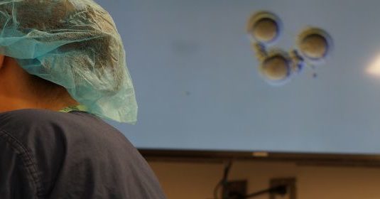 A Lab technician looking through microscopes