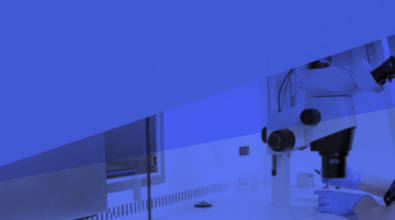 A lab technician looking through a microscope