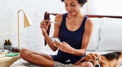 A woman taking a test sitting on her bed with her phone in one hand