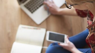 A woman on her phone with a notebook and laptop nearby