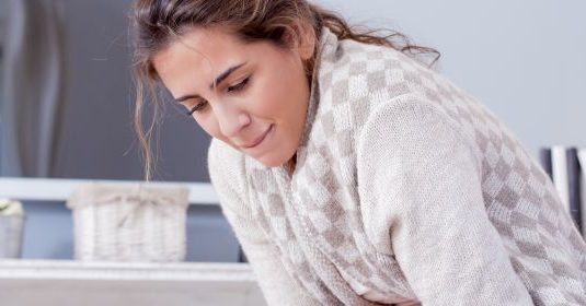 A woman hunched over with her arms folded over her stomach